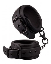 Nastavitelné stahovací pouta z černé veganské umělé kůže vycpané na zápěstí.